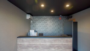 Zona de recepción con diseño moderno, que incluye una pared texturizada, mostrador de recepción e iluminación empotrada en el techo.