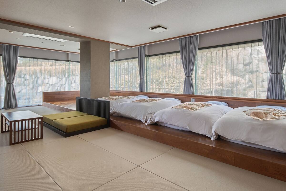 A modern hotel room with a large bed, a small table, and a bench.