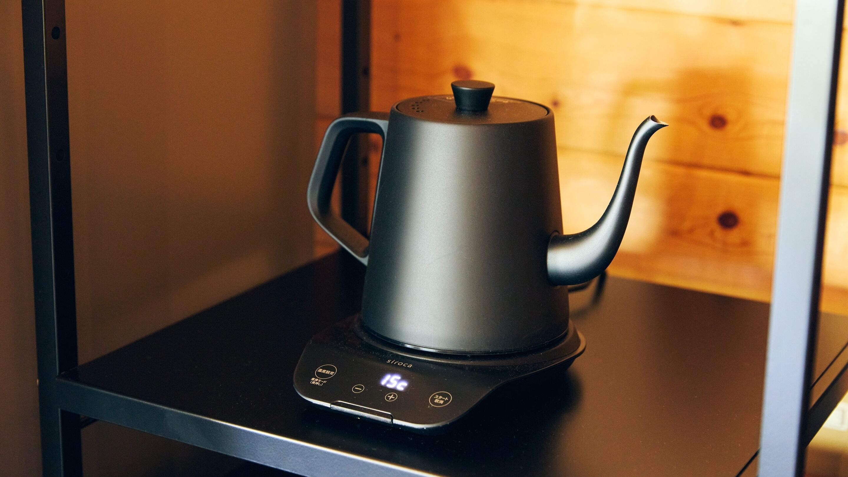 A modern electric kettle with a digital interface on a black countertop.