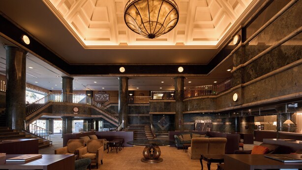 A spacious lobby with a grand staircase, comfortable seating areas, and a large chandelier. - Mission Hills Hotel (Minano)