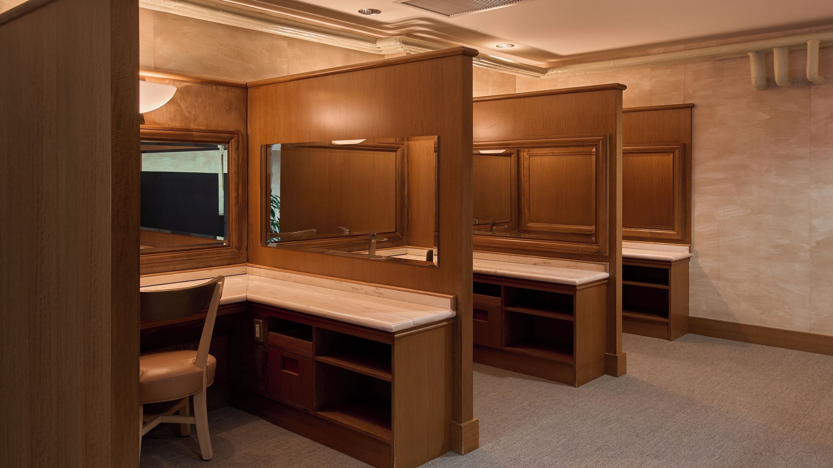 Una habitación de hotel con un espejo grande, armarios de madera, un escritorio y una silla.