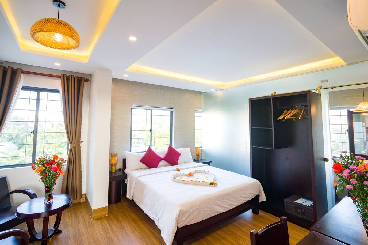 A hotel room with a bed, bedside table, chair, and a wardrobe.