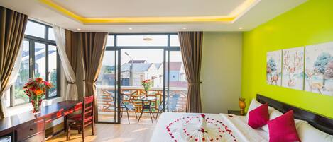 A hotel room with a bed, a desk, and a balcony.