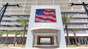 Ein Hotel Eingang mit einer großen US-amerikanischen Flagge und einem Schild mit der Aufschrift 'THE WHARF' über dem Eingang.