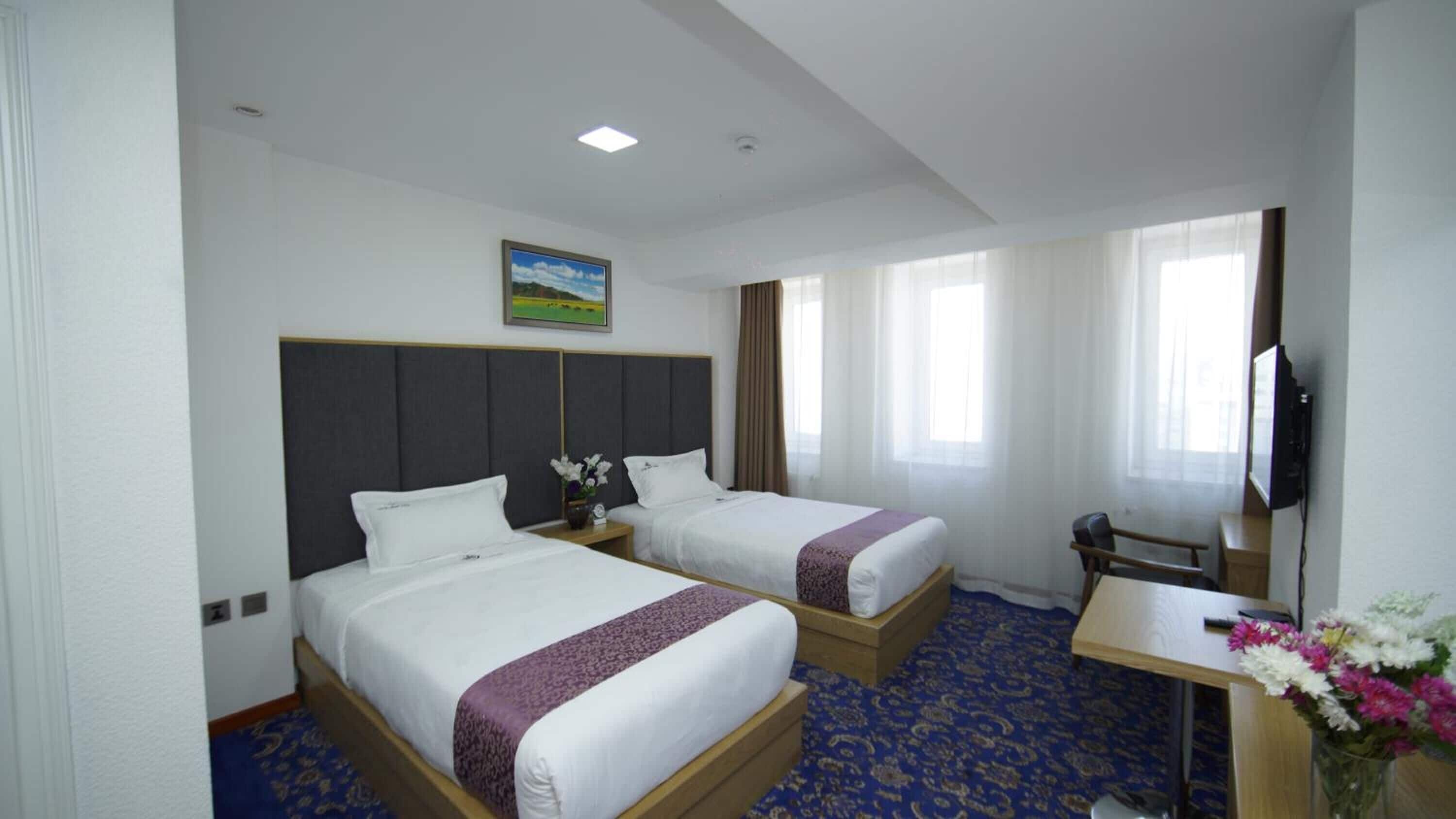 Habitación de hotel con dos camas, un escritorio, un televisor y un cuadro en la pared.