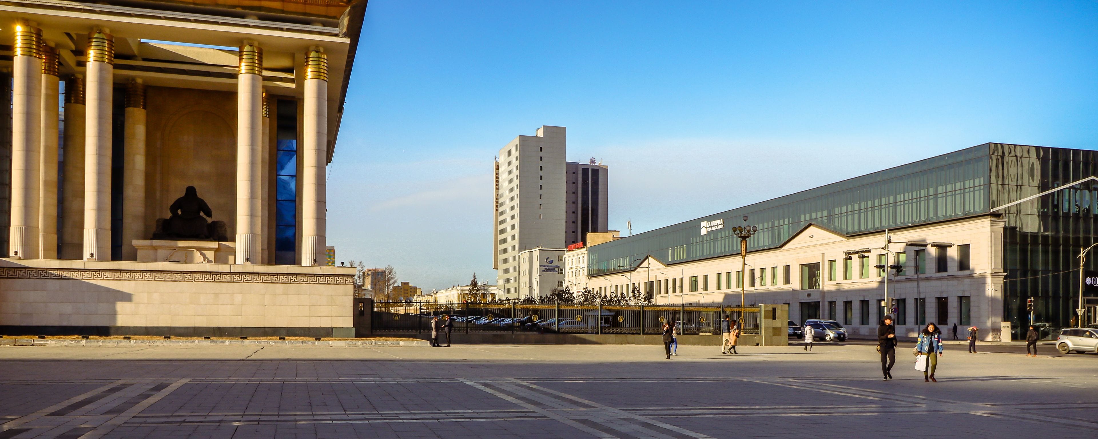 A modern building with large columns and a statue in front.
