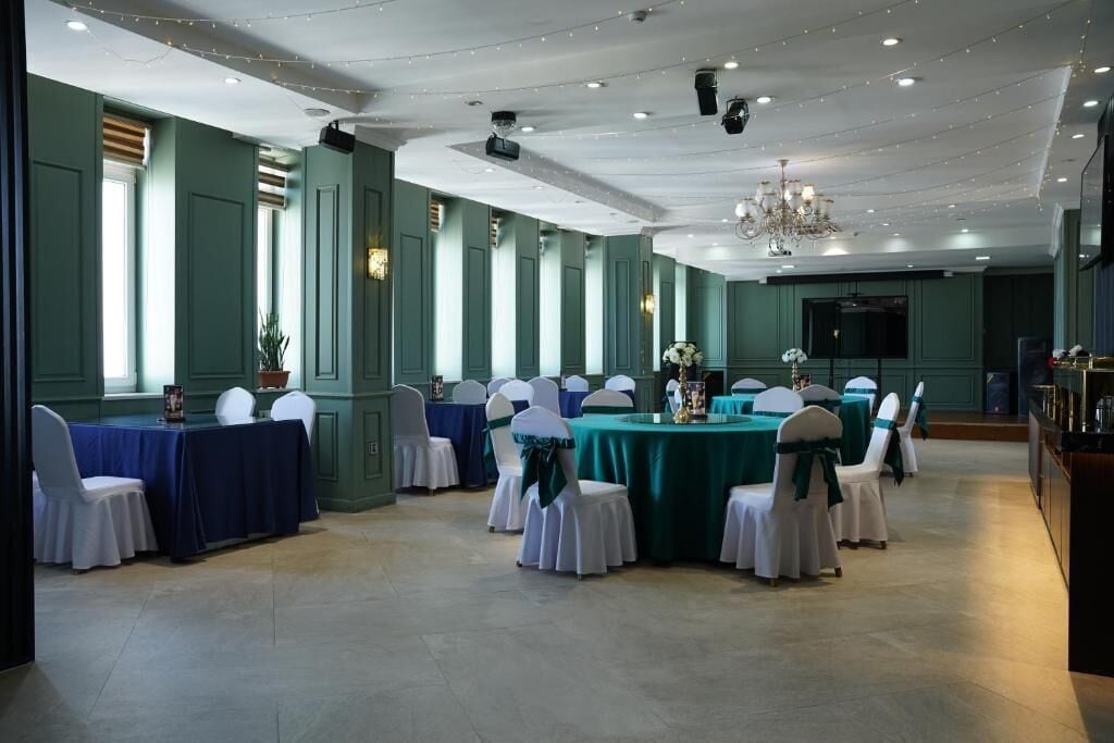 A banquet hall with multiple round tables, white chairs, and teal tablecloths.