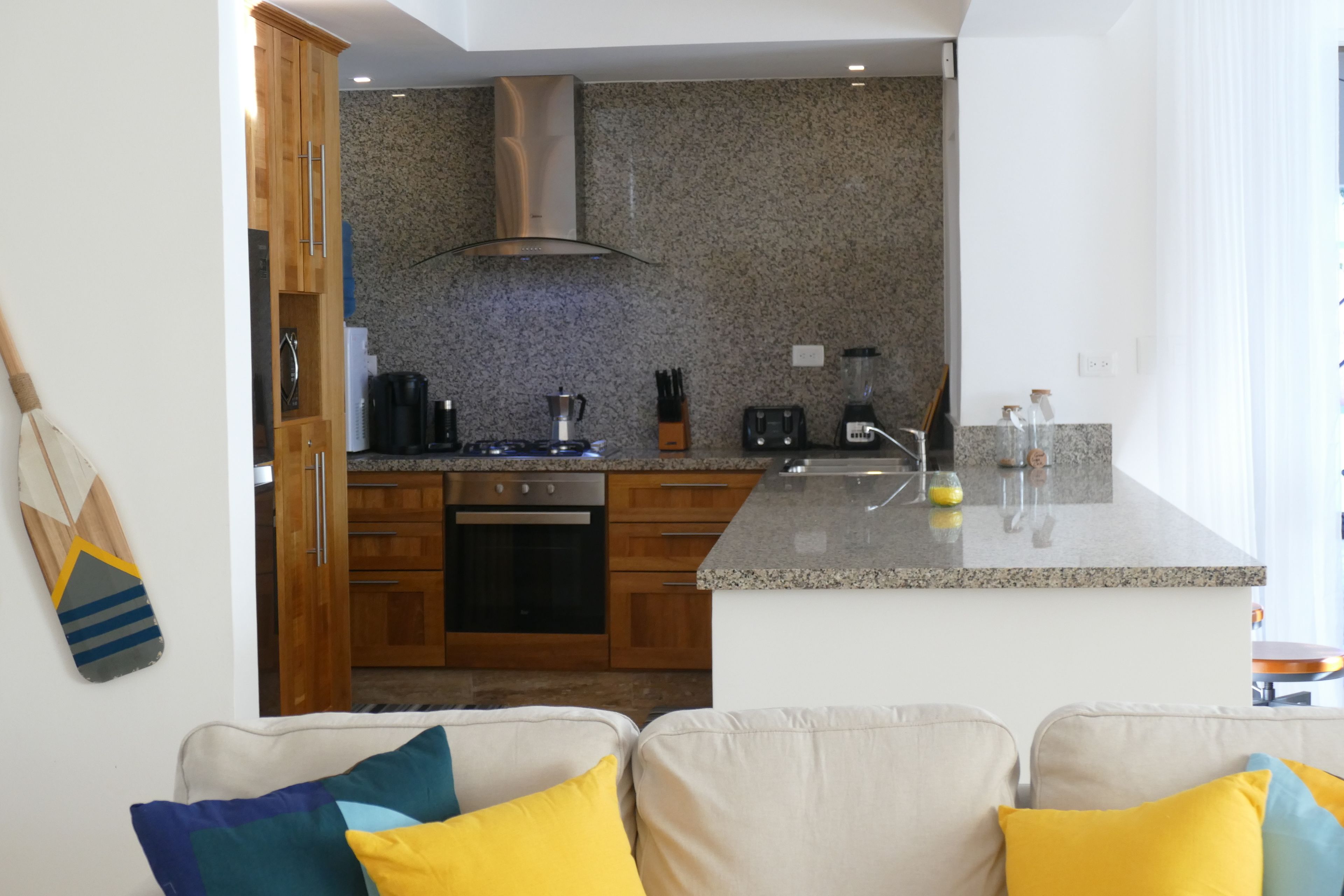 A modern kitchen with wooden cabinets, a granite countertop, and a built-in stove.