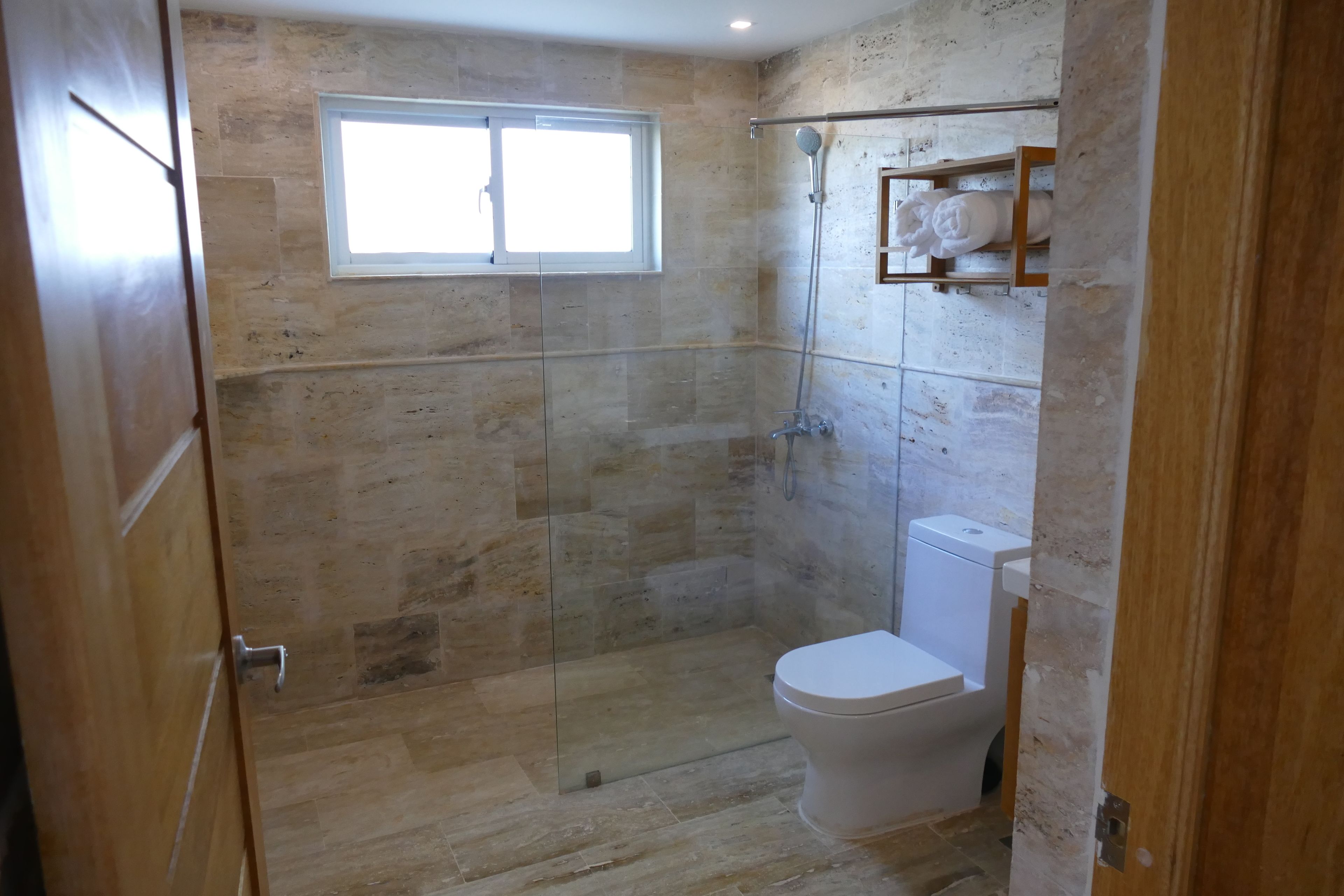 Ein Badezimmer mit Duschkabine, Toilette und Fenster.