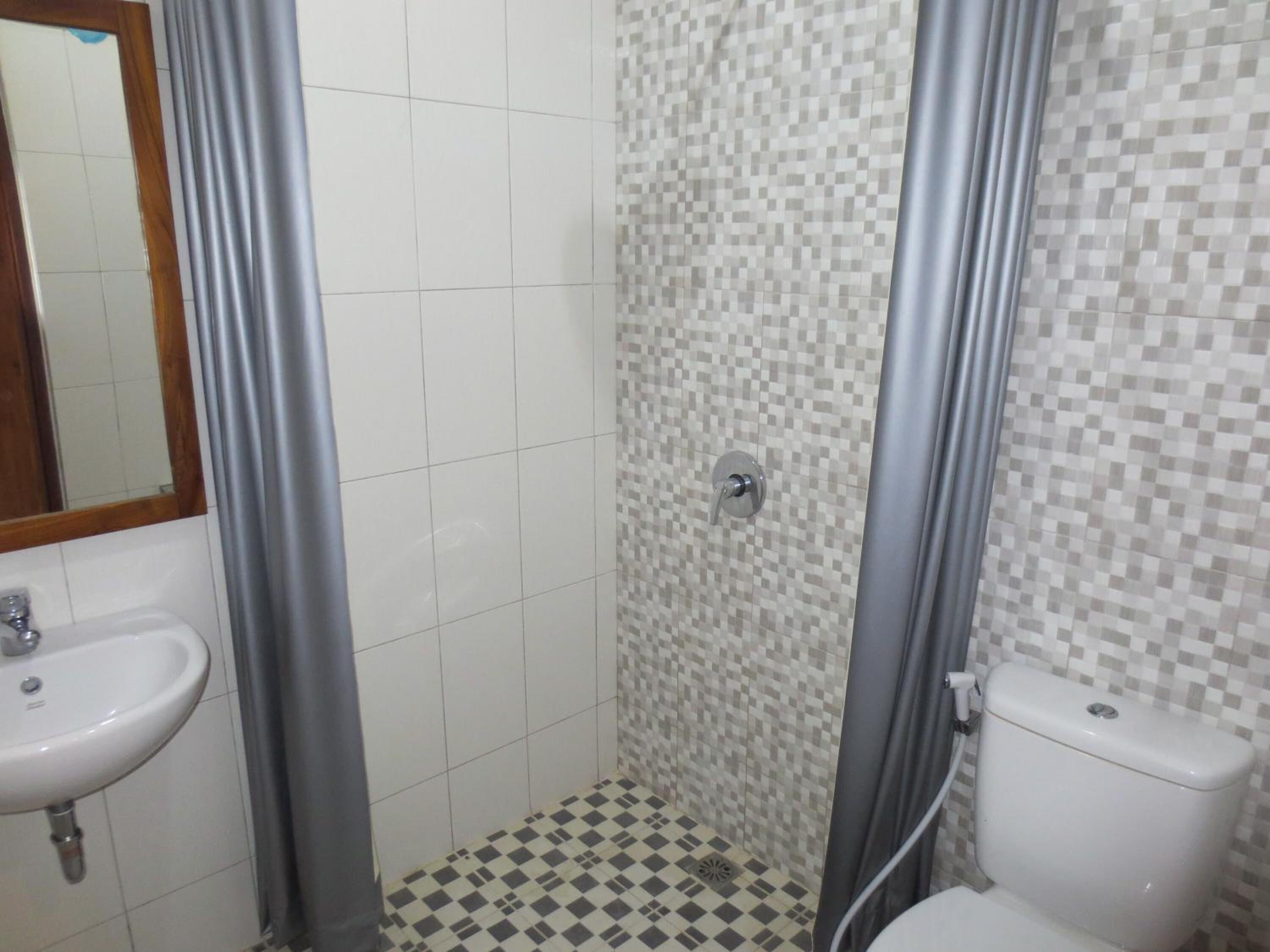 A bathroom with a tiled floor, a sink, a toilet, and a shower area.