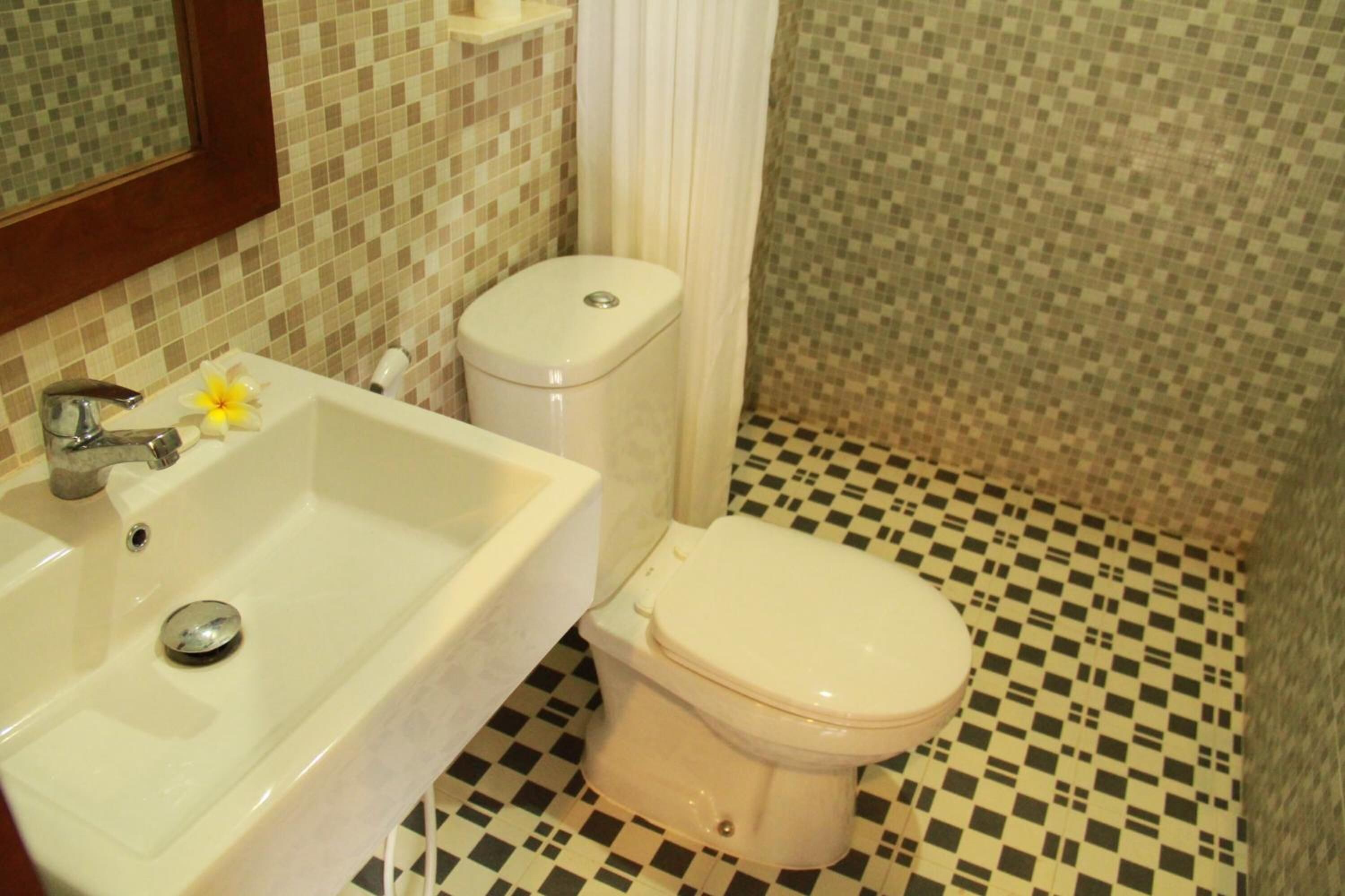 A bathroom with a checkered floor, a white sink, and a toilet.