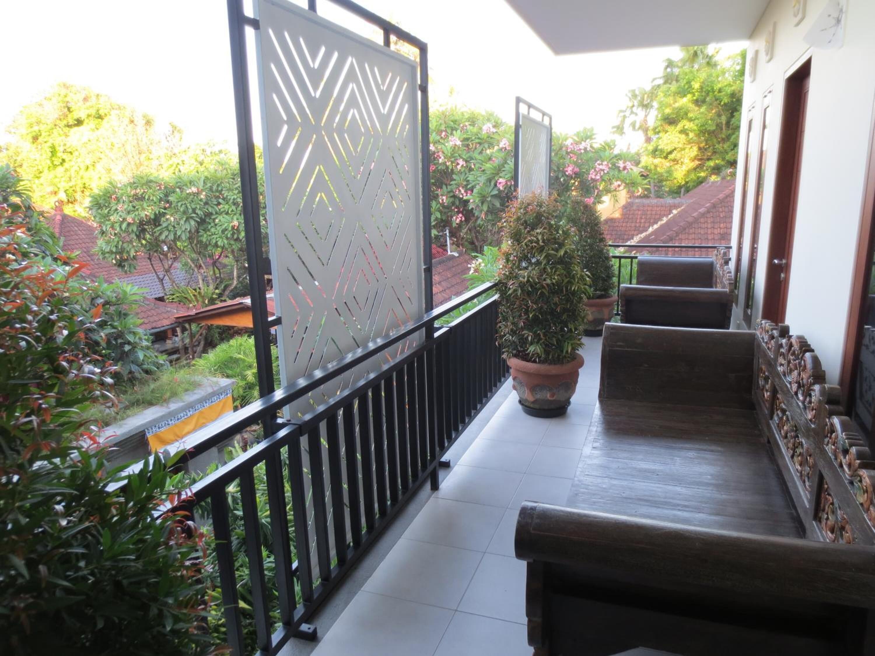 A balcony with a metal railing, a potted plant, and a wooden bench.