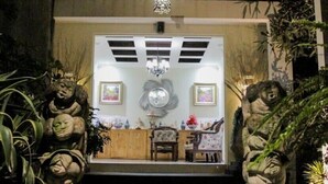 Uma entrada em estilo japonês tradicional, com estátuas de pedra e teto de madeira.