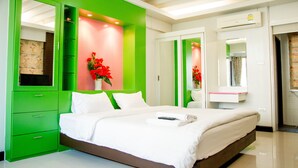 Um quarto moderno com parede verde de destaque, uma cama grande com roupa de cama branca, uma mesa de cabeceira e um espelho.