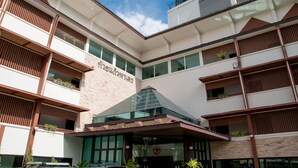 Um hotel de vários andares com design arquitetônico moderno, apresentando varandas com plantas, janelas amplas e uma entrada imponente.