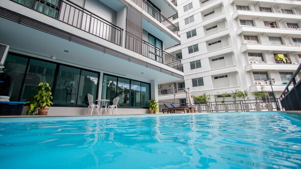 Um hotel moderno com piscina, varandas e plantas em vasos.