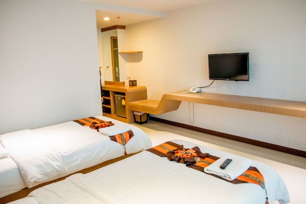 A hotel room with two beds, a desk, a TV, and a small seating area. - Huay Kaew Palace 1 (Chiang Mai)