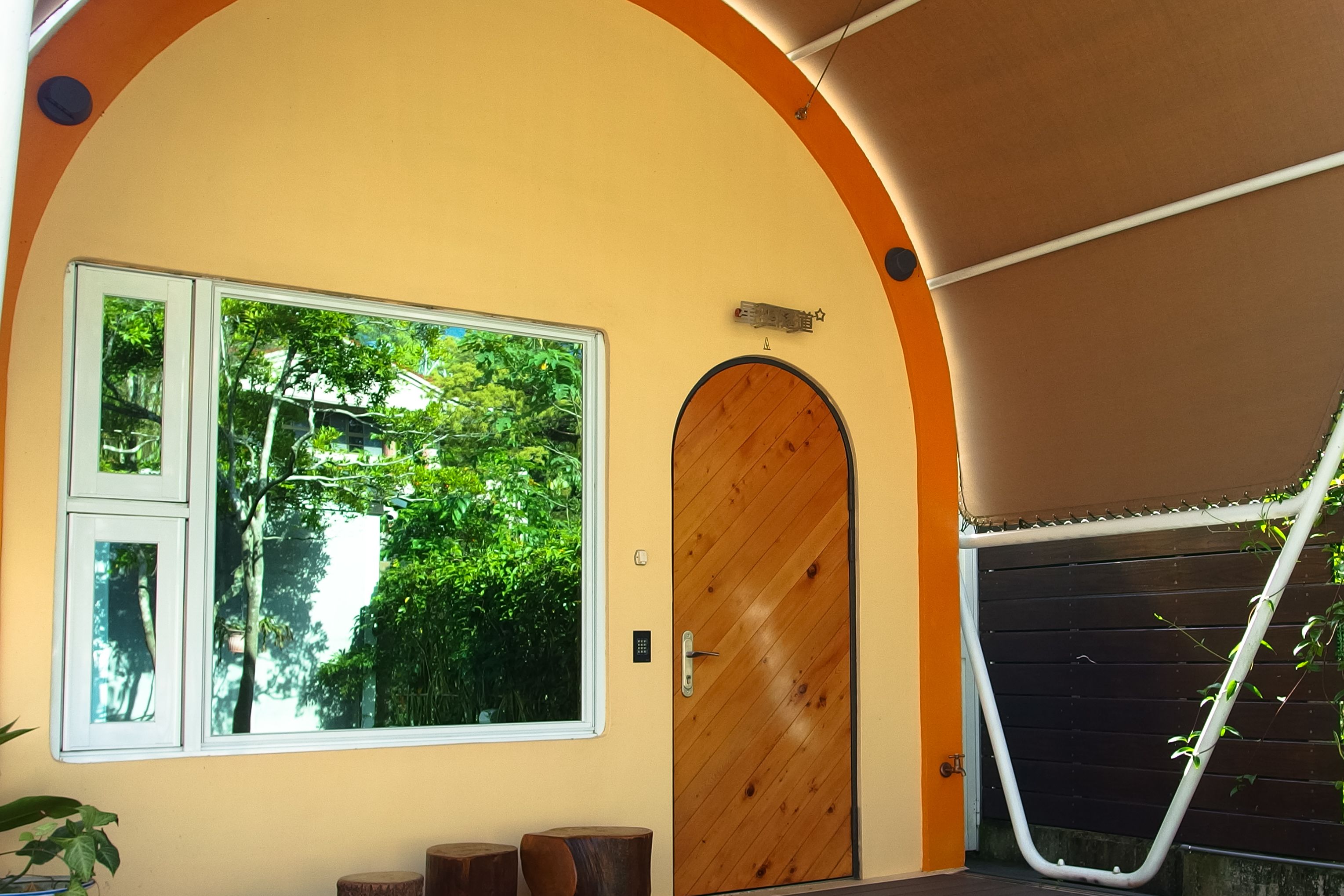 A room with a large window, a wooden door, and a curved ceiling.