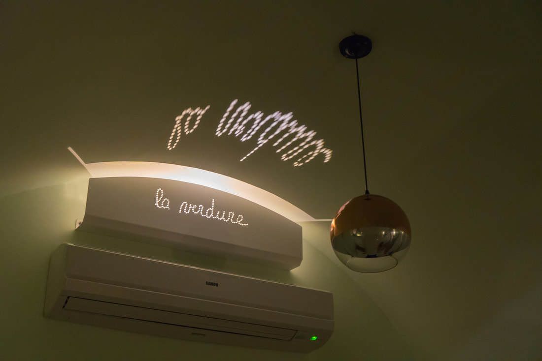 Un aire acondicionado de pared con un letrero de neón encima que dice 'la merde'.