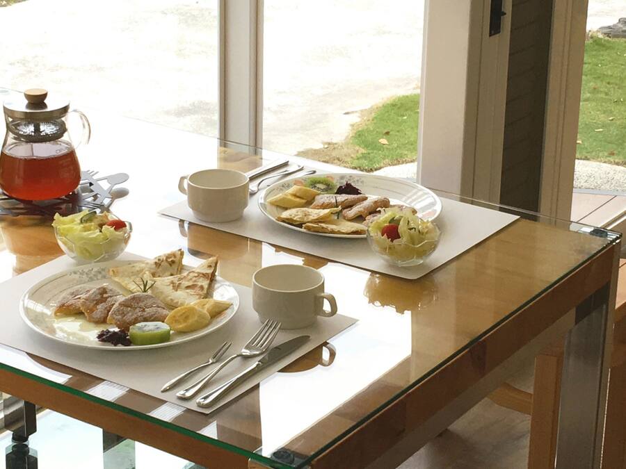 A breakfast table with plates of pastries, a coffee pot, and a bowl of fruit.