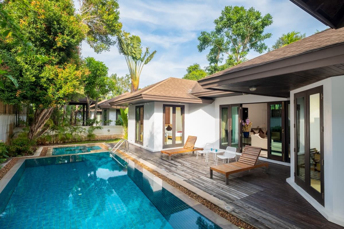 A modern house with a swimming pool, wooden deck, and large windows.