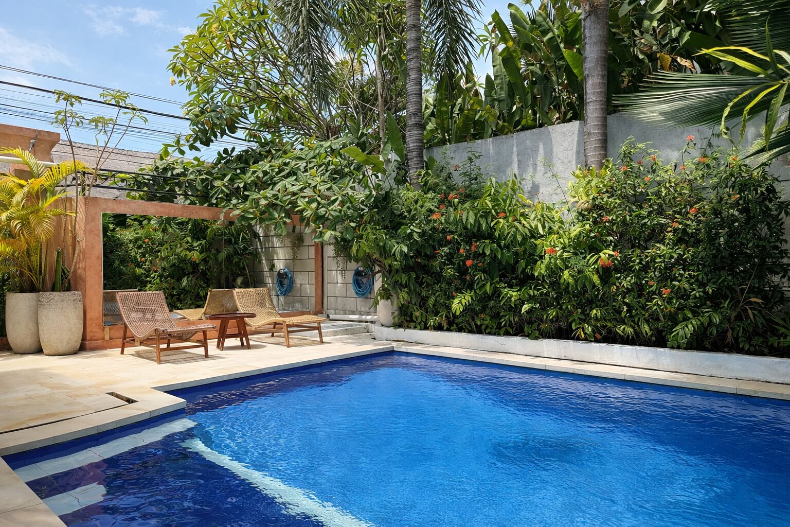 Une piscine dotée de chaises longues et agrémentée de plantes tropicales.