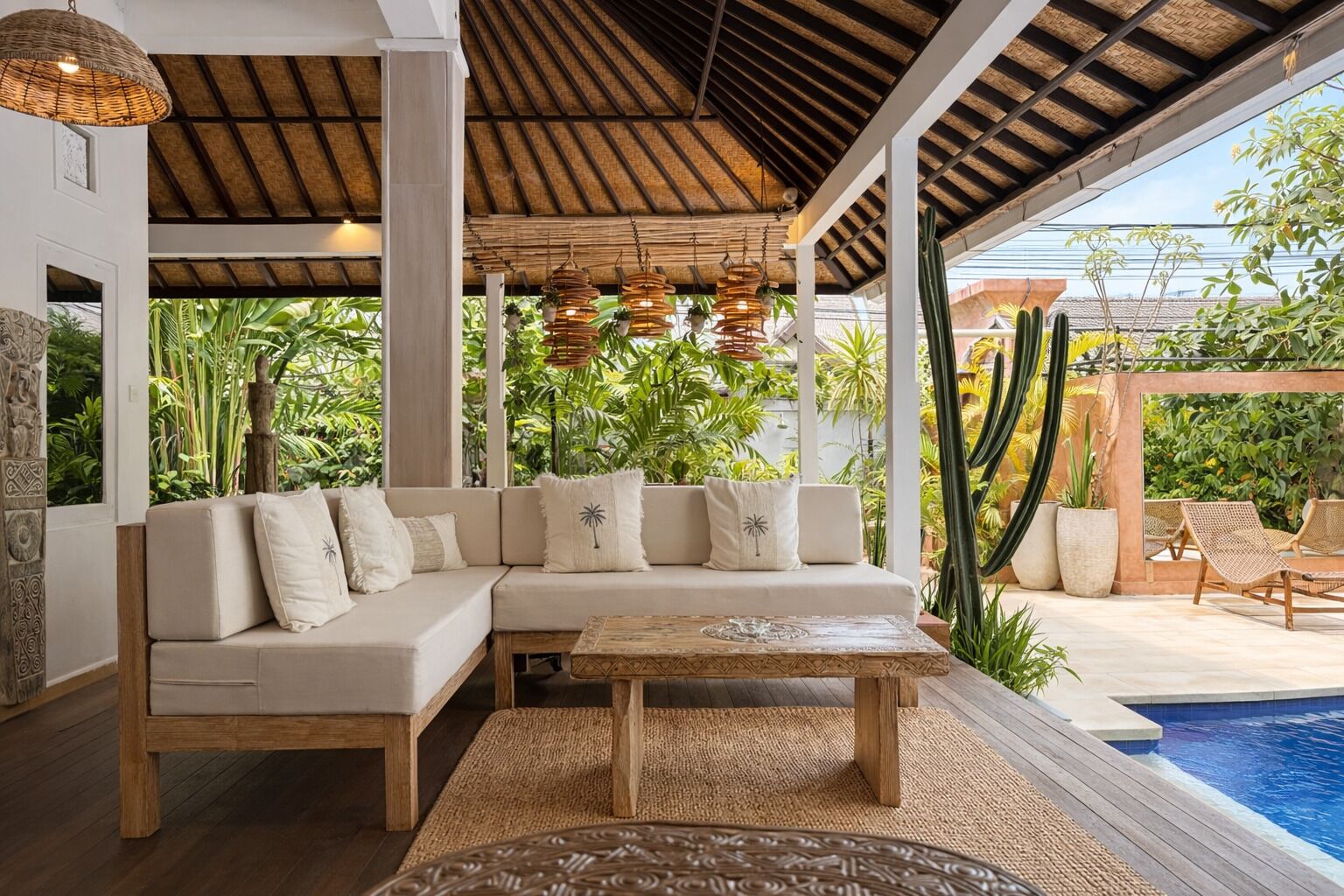 A covered outdoor seating area with a sofa, a coffee table, and hanging lights.