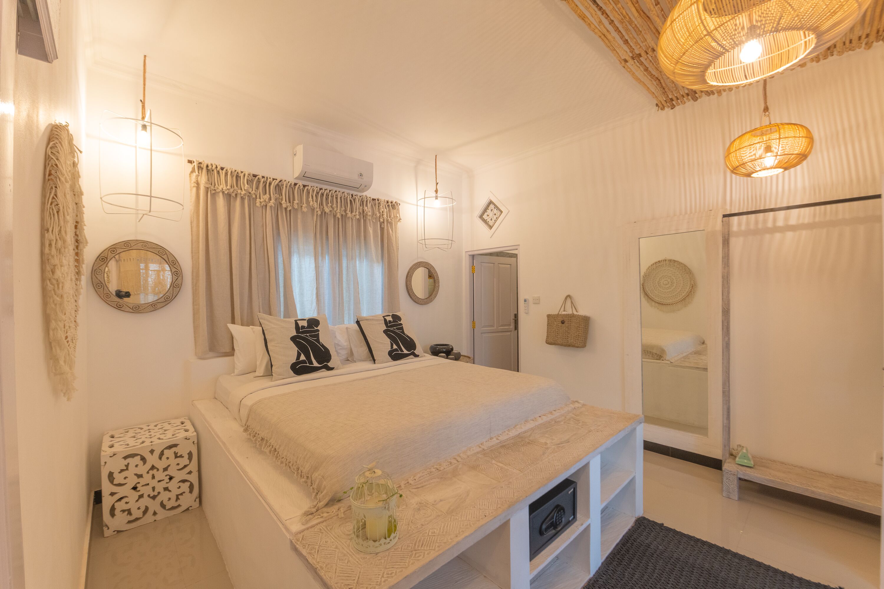 A bedroom with a bed, bedside tables, a mirror, and a wardrobe.