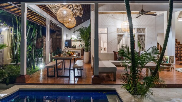 A poolside area with a dining table and chairs, a seating area with a sofa, and a ceiling fan. - Smiling Cactus Villa (Seminyak)