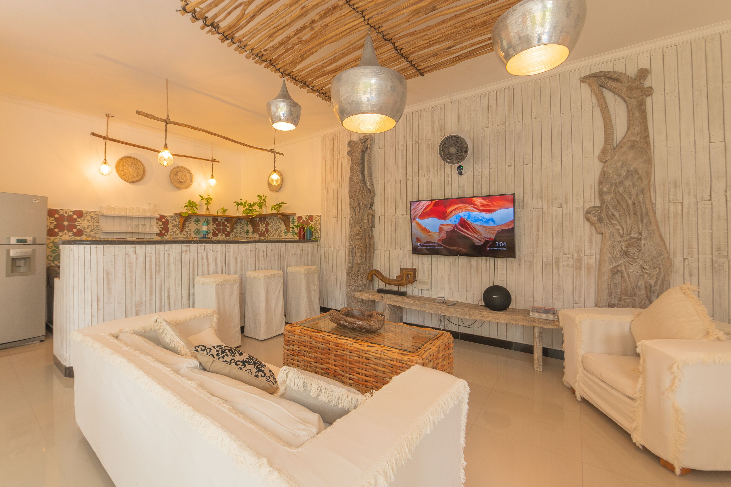 Uma sala de estar moderna com um sofá, poltronas, uma mesa de centro e uma televisão.