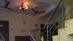 Una escalera con barandillas de metal, un ventilador de techo y una planta en maceta.