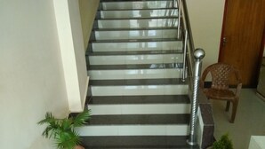Una escalera con barandilla de metal, plantas en macetas y una silla de madera.