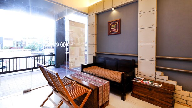 A modern living room with a sofa, wooden chairs, a coffee table, and a bookshelf. - Hotel O Hills Residence (Kuching)