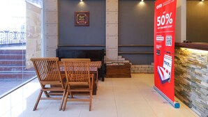 A modern hotel lobby with a wooden reception desk, a fireplace, and a large promotional banner offering a 50% discount. - Hotel O Hills Residence (Kuching)