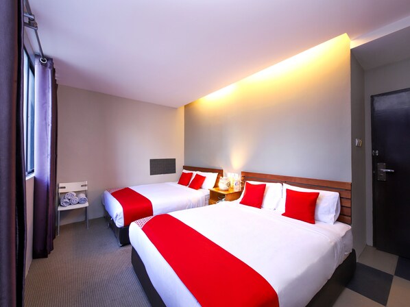 Habitació d'hotel amb dos llits, una tauleta de nit, una làmpada penjada a la paret i una porta.