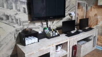 A room with a television mounted on a textured wall, a wooden cabinet with various items, and a speaker on the right.