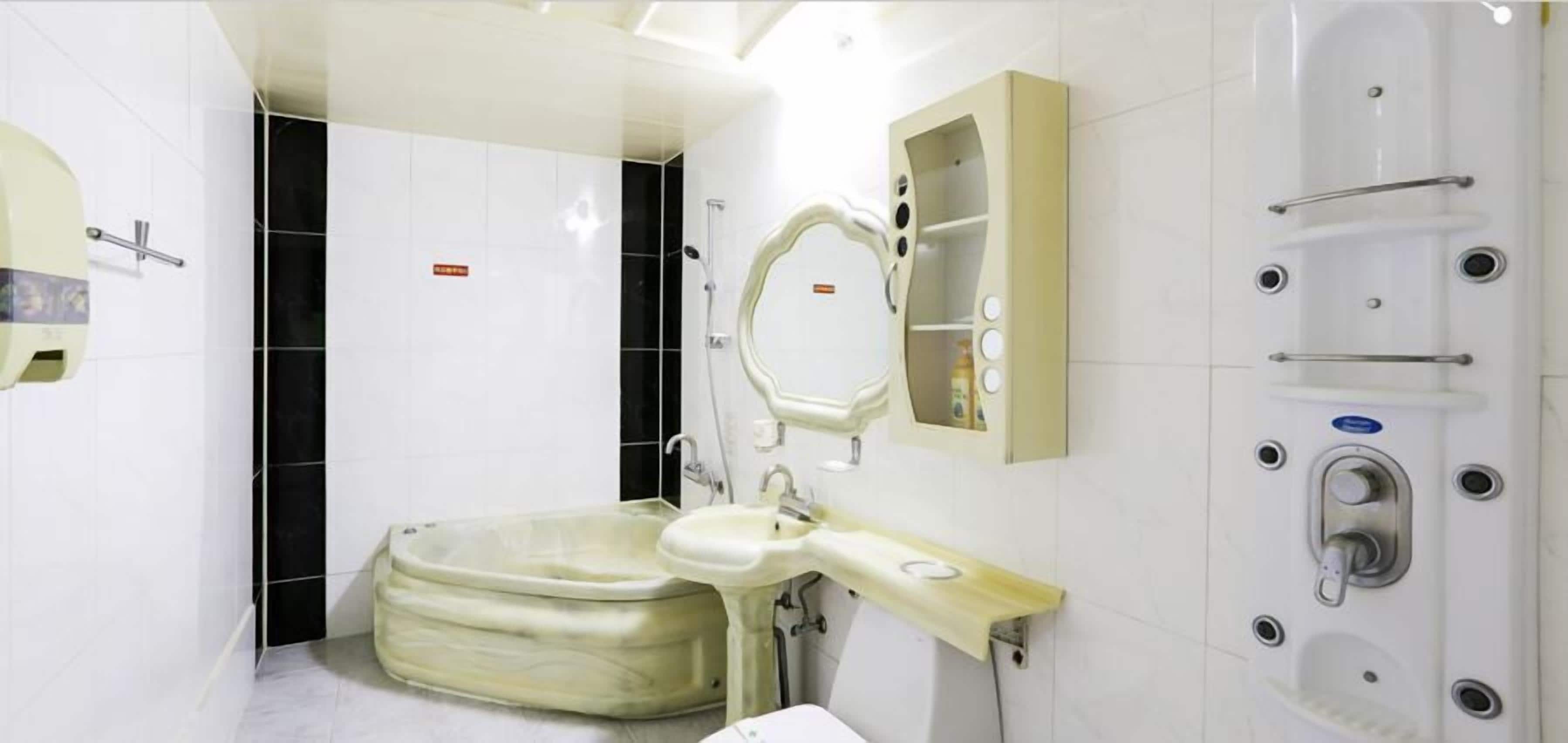 A bathroom with a bathtub, a sink, a mirror, and a shower enclosure.