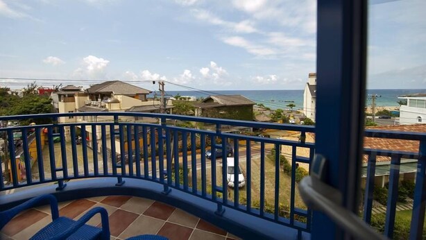 A balcony with a view of the sea and neighboring houses. - Haisu Homestay (Hengchun)