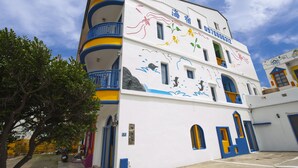A multi-story building with colorful exterior artwork, balconies, and a clear sky. - Haisu Homestay (Hengchun)
