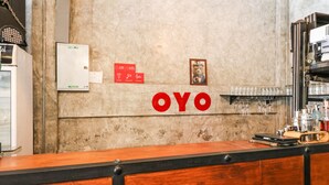 Een bar met een houten toonbank, een bord met de tekst 'OYO' in rode letters, en een plank met glazen en flessen.