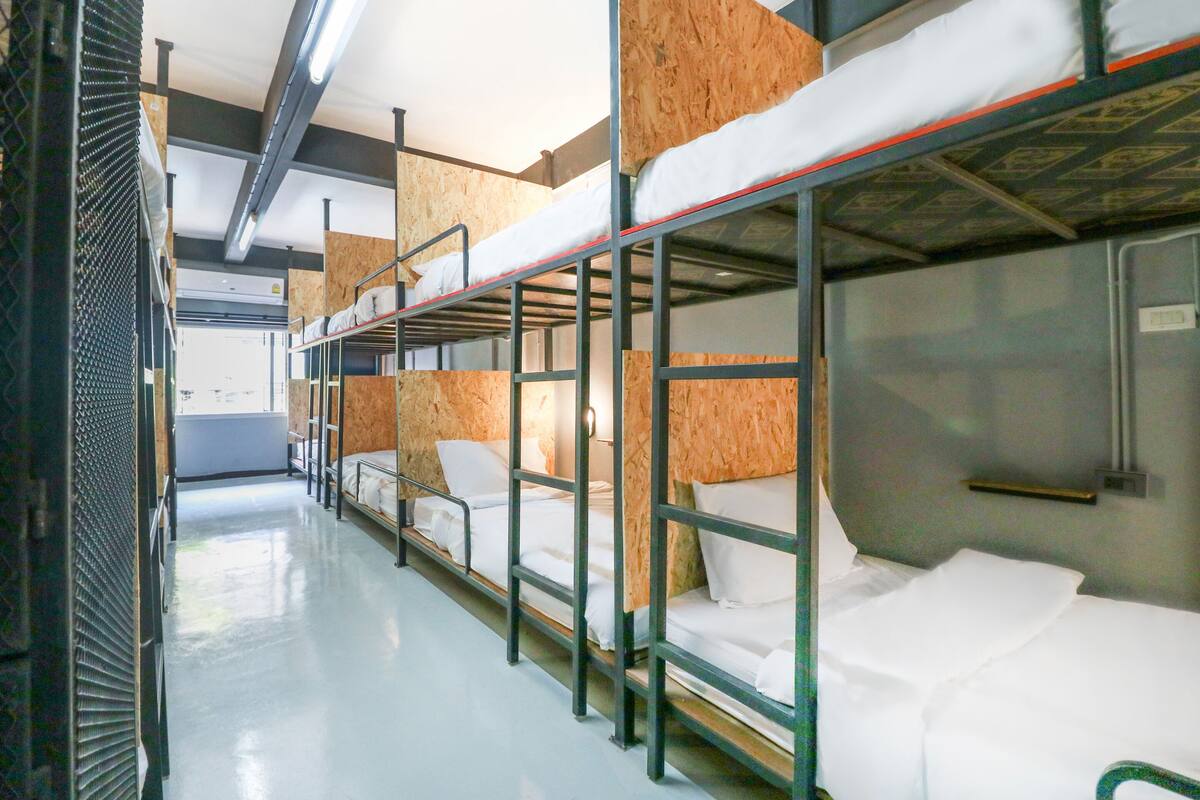 Een treinwagon met slaapplekken, houten lambrisering en metalen leuningen.