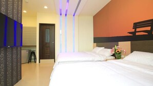 A hotel room with a large bed, a desk, and a TV mounted on the wall. - Amethyst Bay (Magong)