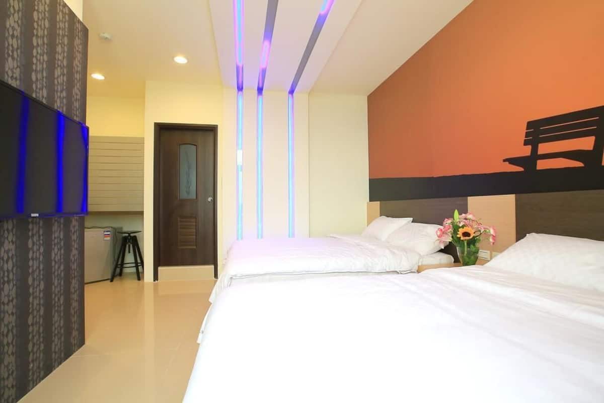 A hotel room with a large bed, a desk, and a TV mounted on the wall.