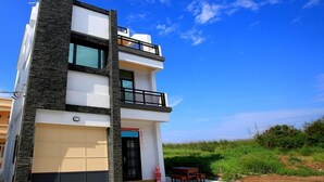A modern two-story building with a flat roof, large windows, and a balcony. - Amethyst Bay (Magong)