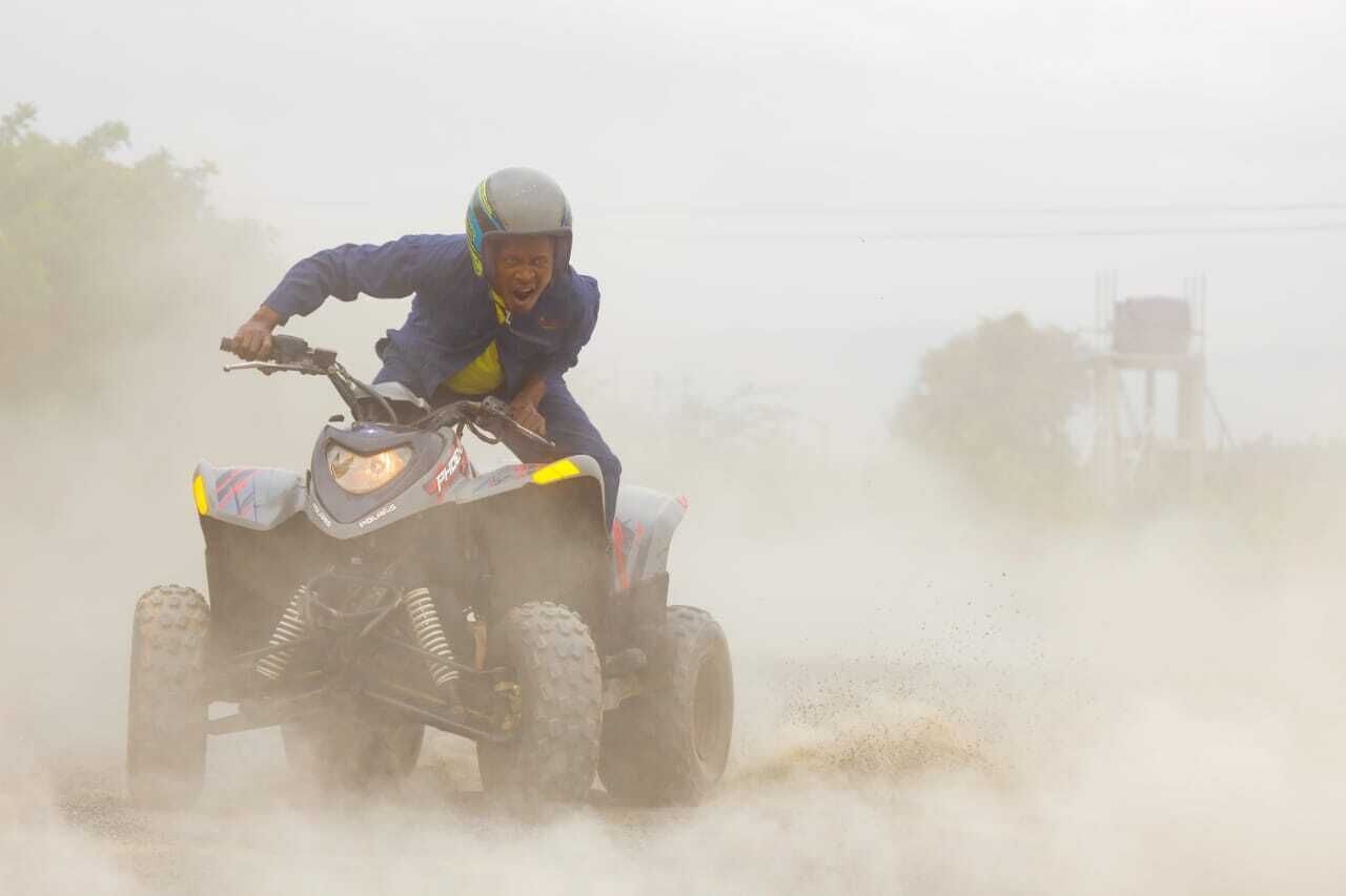 A person riding a quad bike on a dusty road.