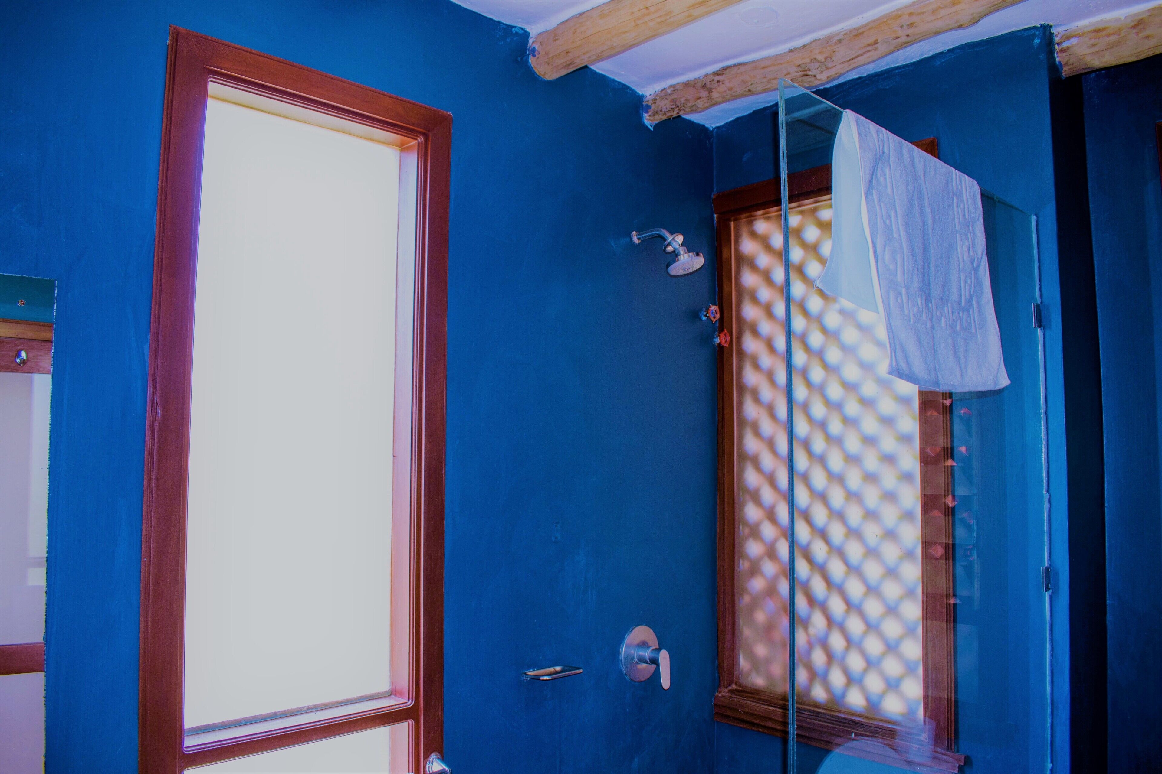 A bathroom with a large window, a shower, and a towel hanging on a rack.