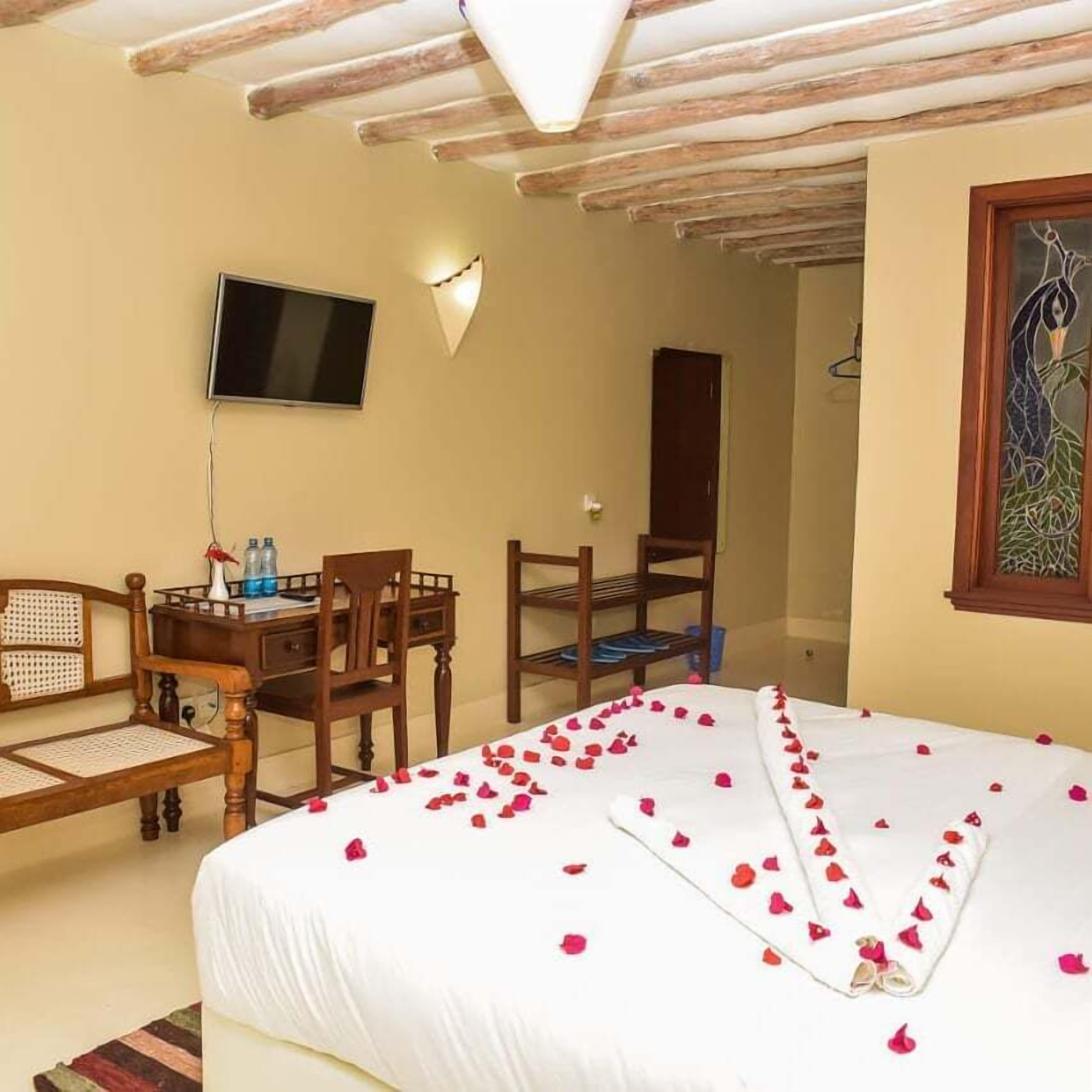 Una habitación de hotel con cama, escritorio, silla, televisor y puerta.