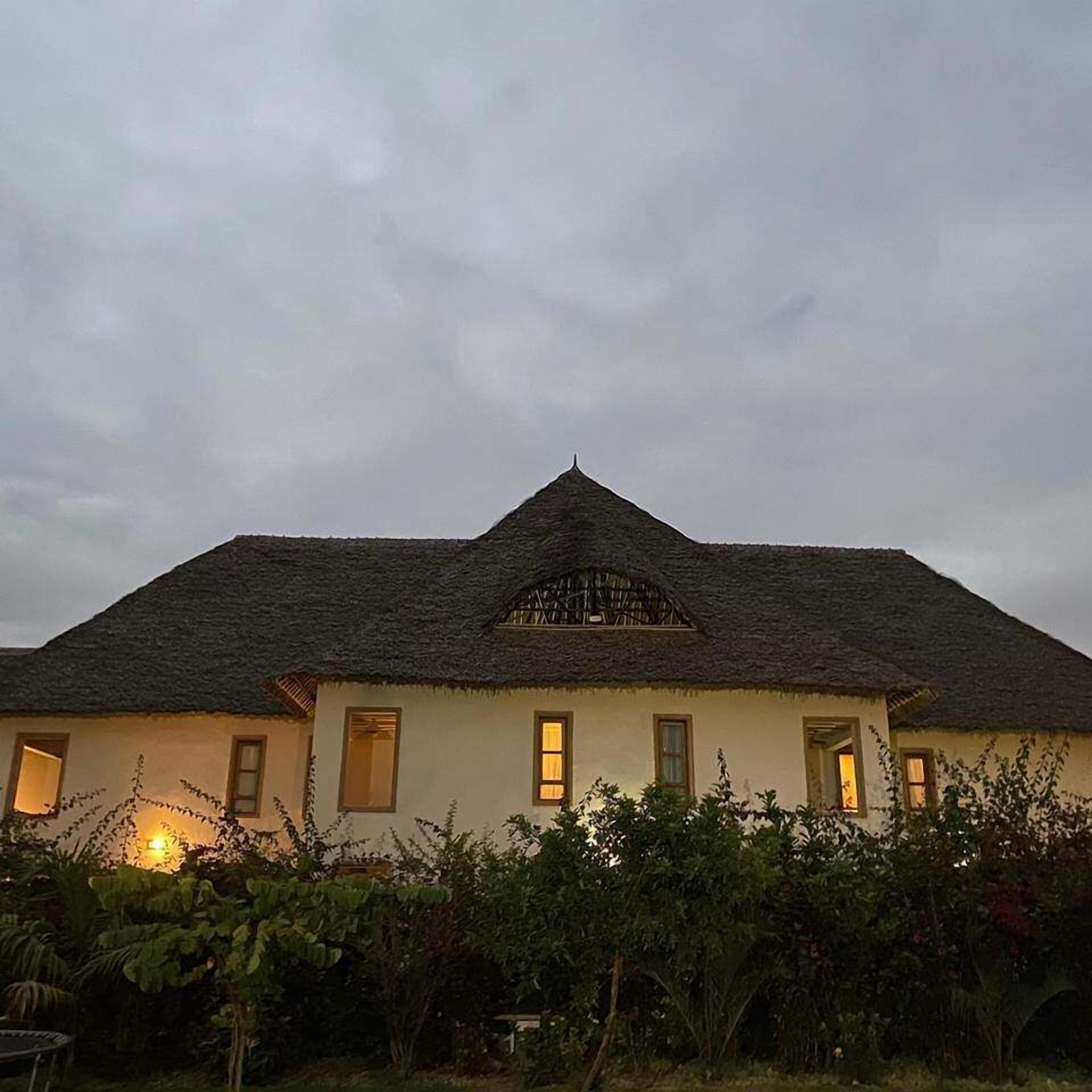 A house with a thatched roof, multiple windows, and a garden in front.