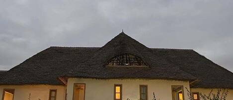 A house with a thatched roof, multiple windows, and a garden in front.