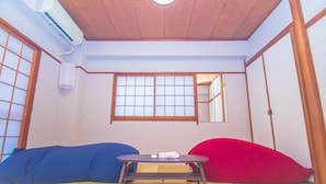 A traditional Japanese room with tatami flooring, a low table with cushions, and sliding doors. - AMP FLAT Nishijin5 (Fukuoka)